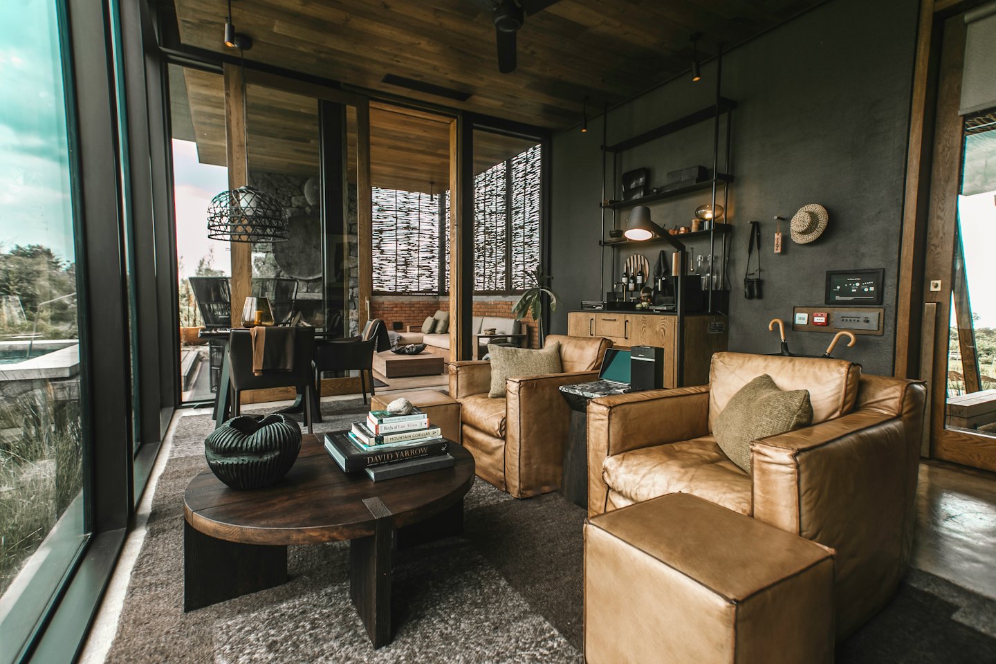 Modern lounge featuring leather chairs and windows overlooking green foliage.