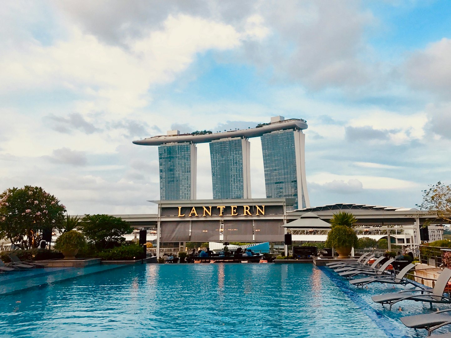 Modern infinity pool on a skyscraper terrace with lounge chairs.
